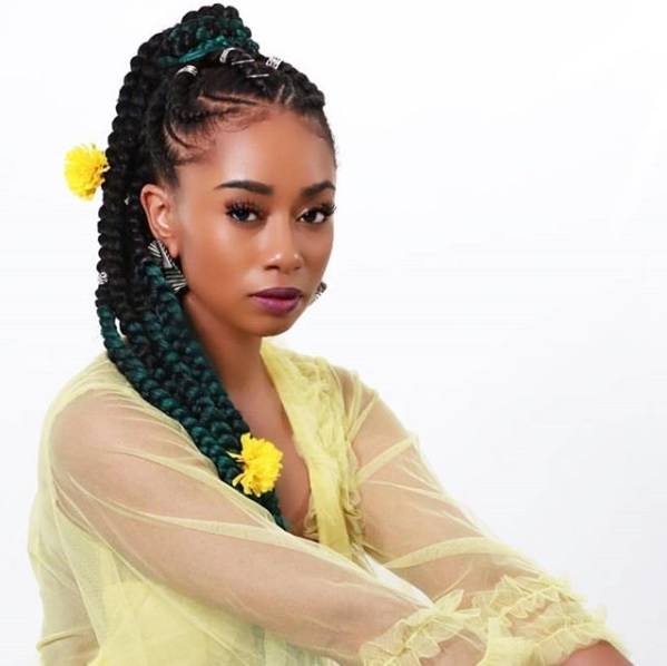 Protective hairstyles: Woman with her natural hair in a Ghana braid ponytail with yellow flowers in it