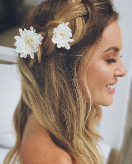 side view of woman with half up crown braid with two white flowers placed in the braid