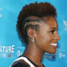 issa rae with an afro mohawk with tiny cornrows either side with metallic golden thread woven through