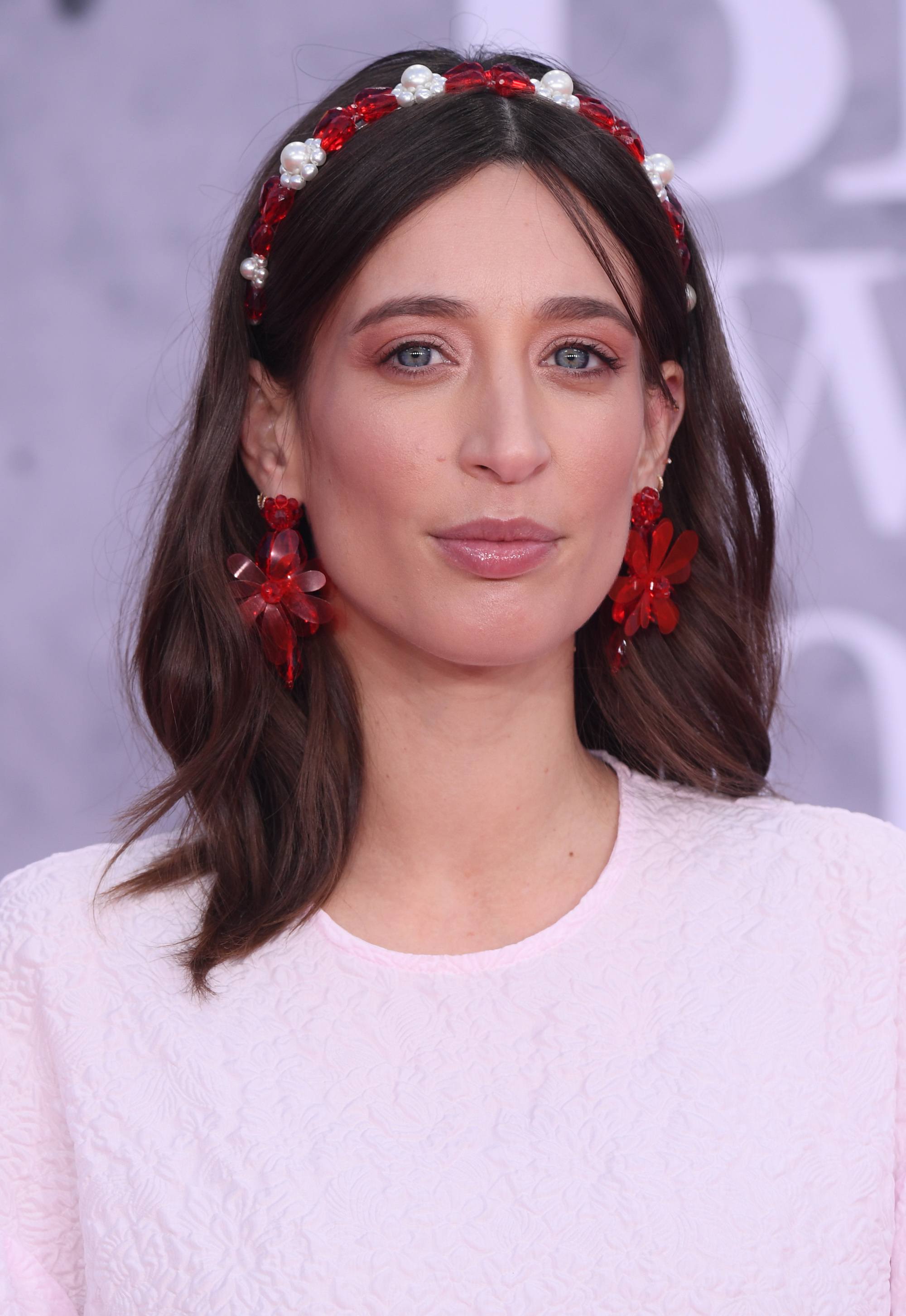 Grown out bangs: Laura Jackson with brown shoulder length hair wearing a red and white headband and light pink dress.