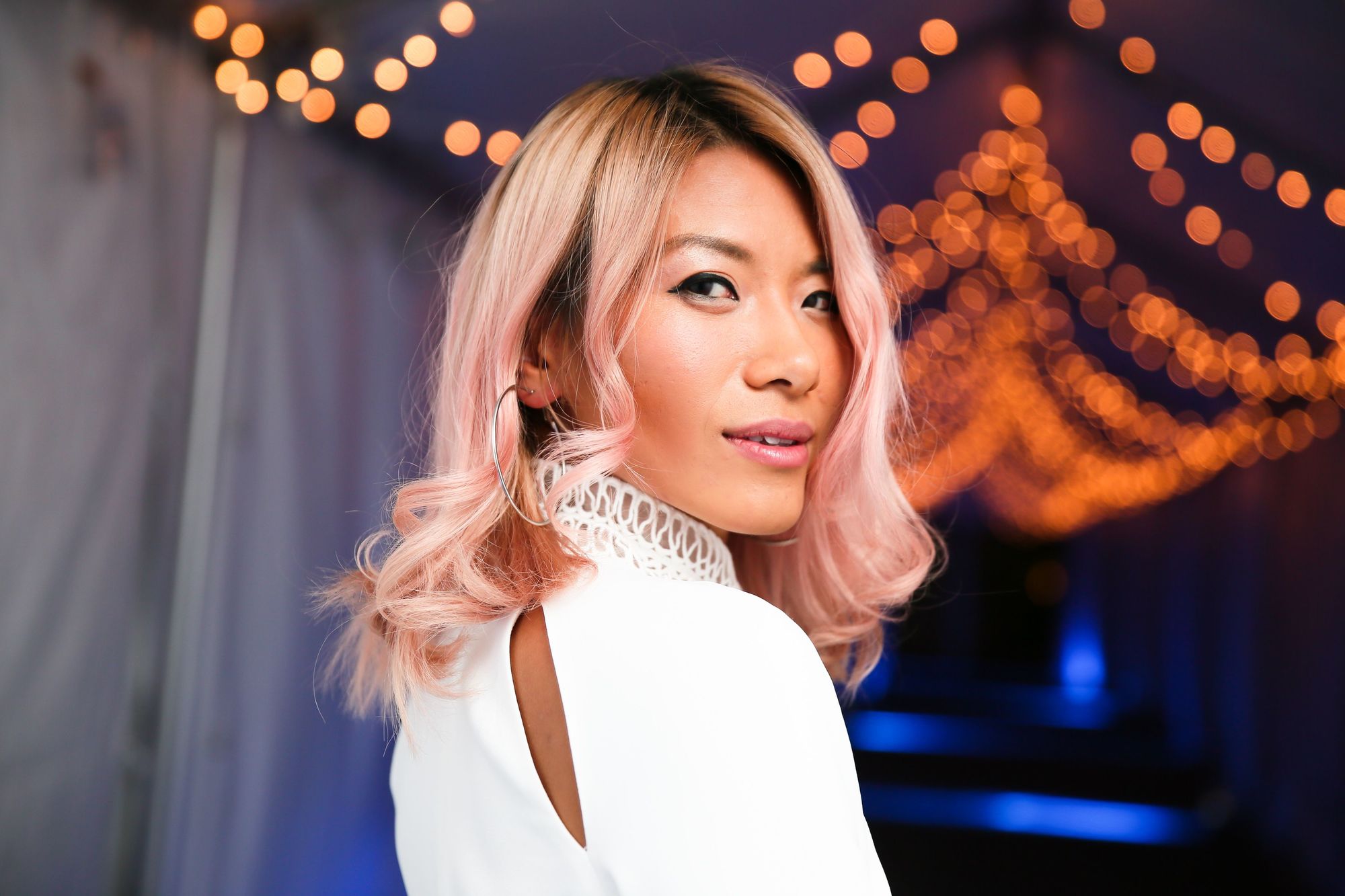close up shot of may kowk with rose gold hair, wearing white and posing for picture