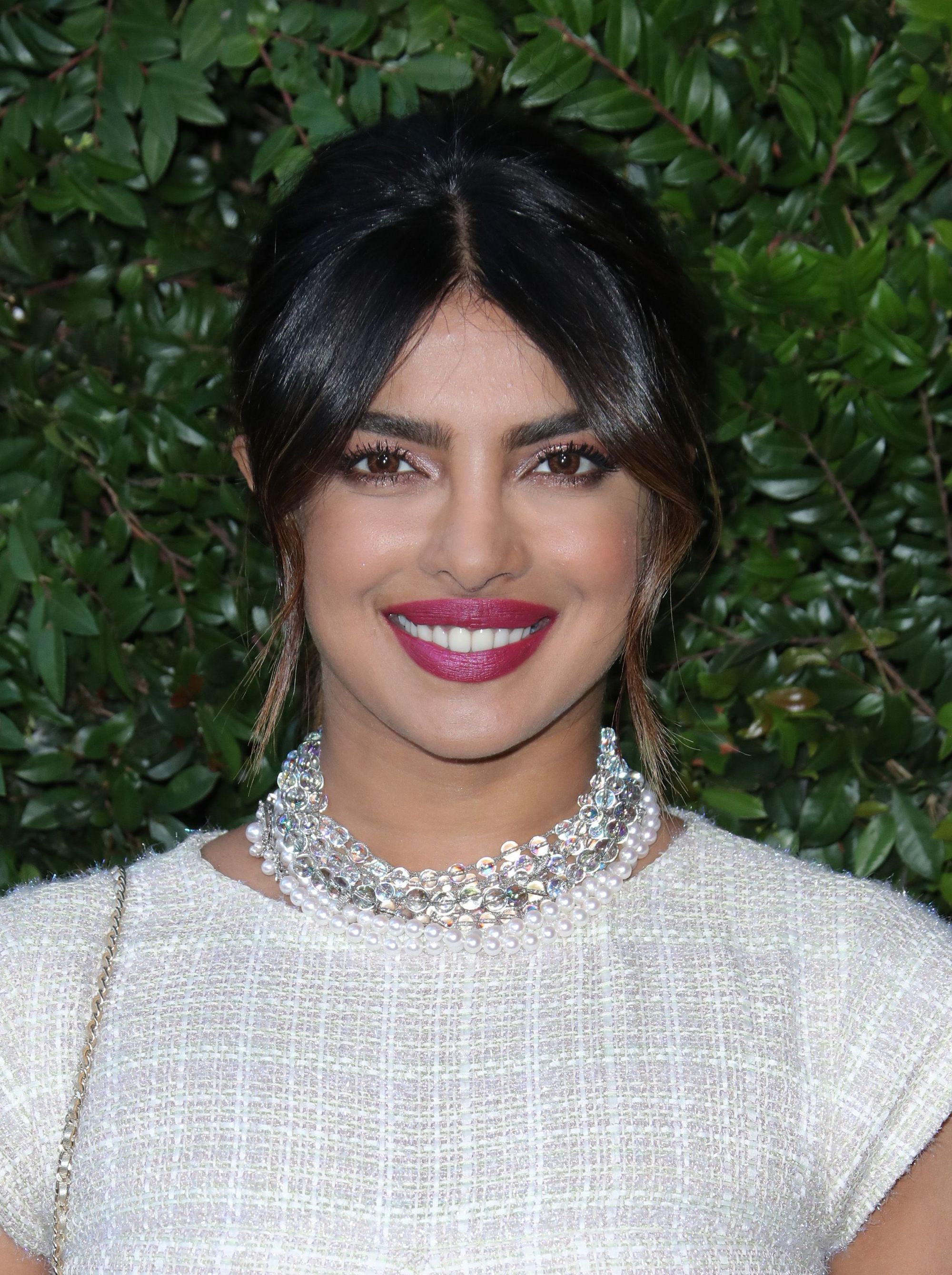 Growing out bangs: Priyanka Chopra with brown hair in updo with long Bardot bangs.