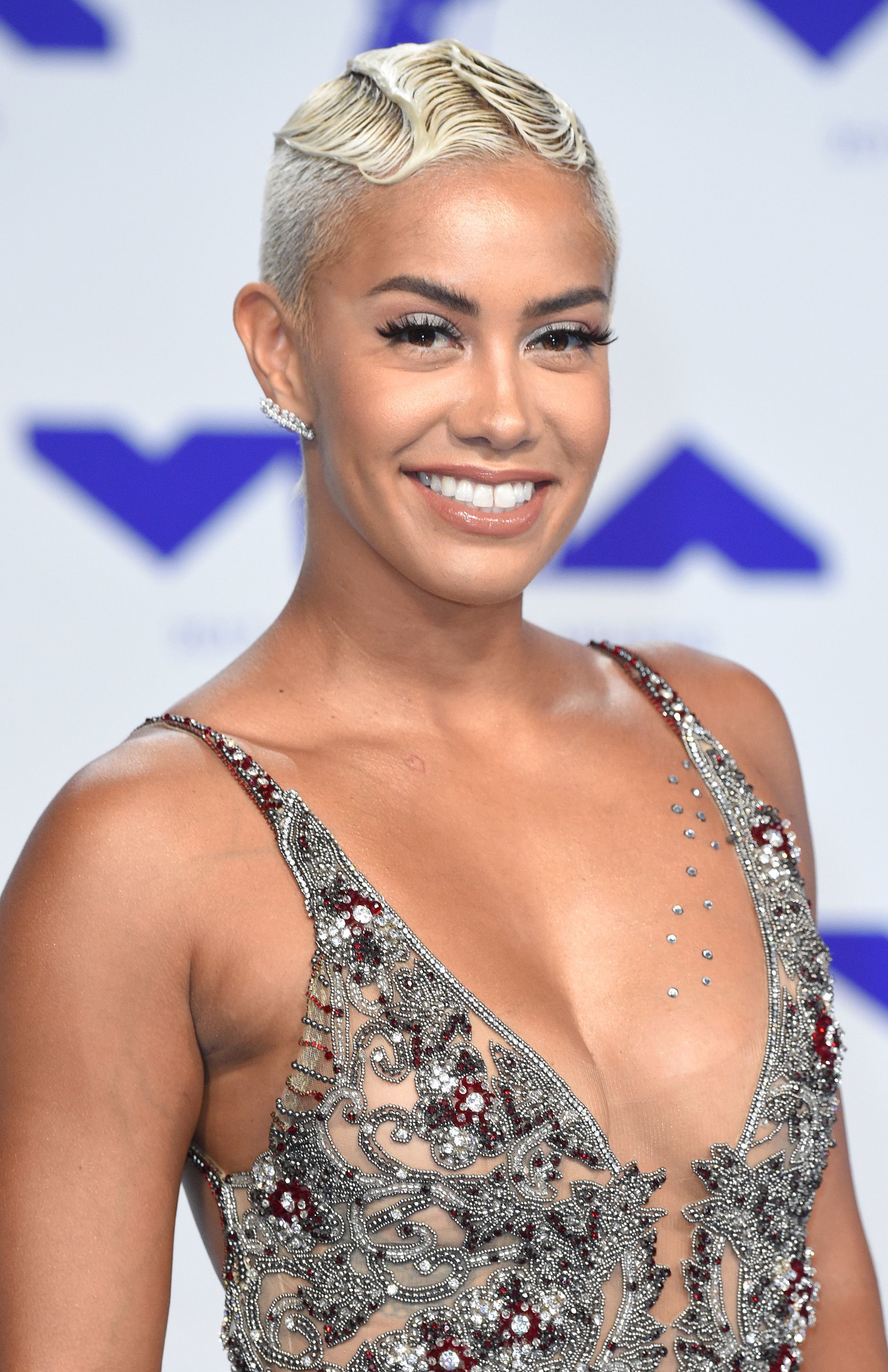 close up shot of sibley scoles with very short blonde hair styled into finger waves, wearing silver dress and posing on the red carpet