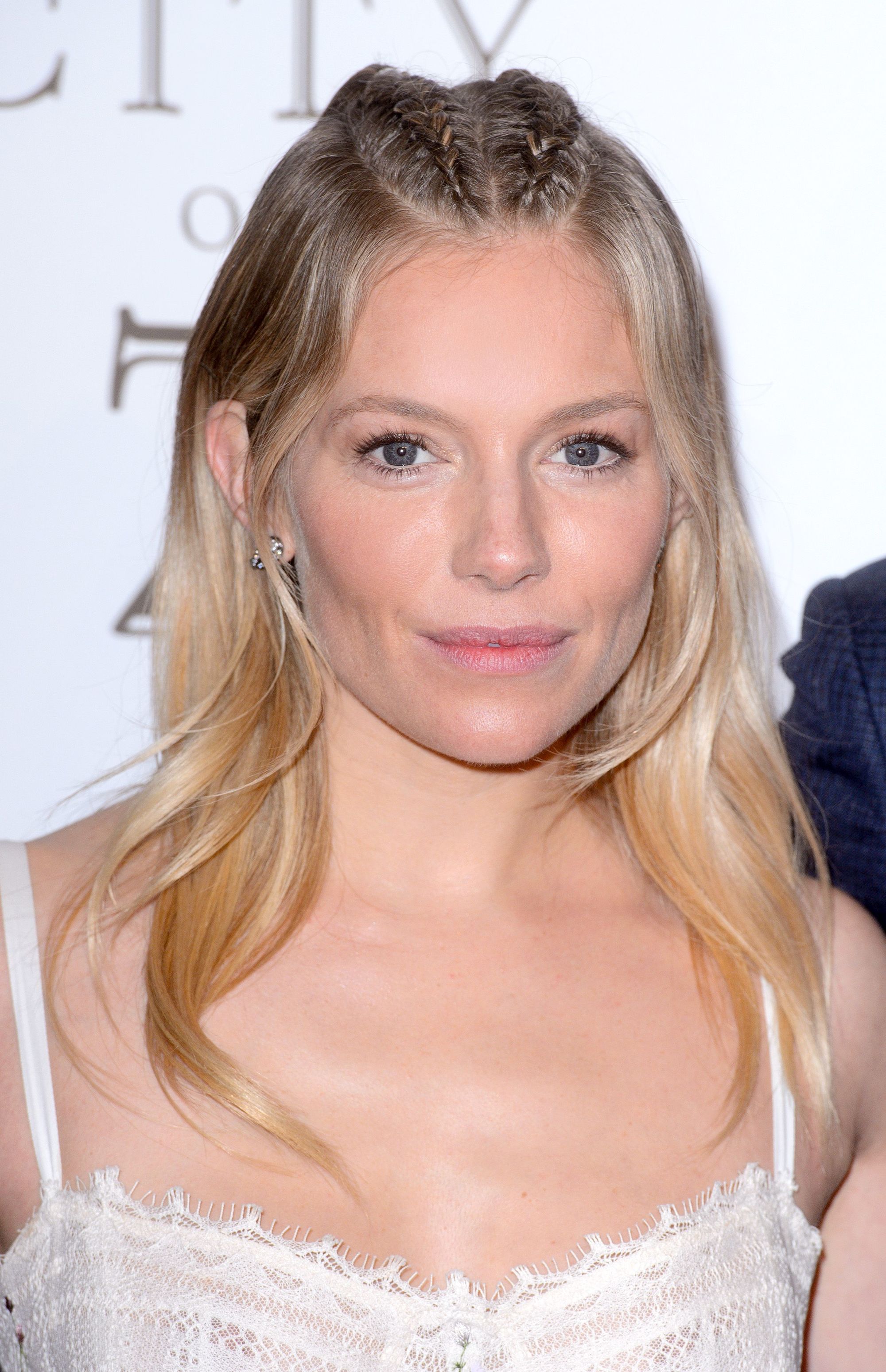 Growing out bangs: Sienna Miller with blonde medium length hair with cornrow braids down the centre.
