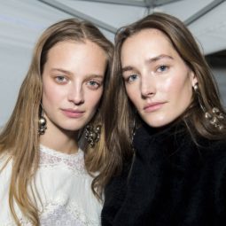 the best flat iron spray: close up shot of two models backstage with sleek, shiny strands, wearing black and white
