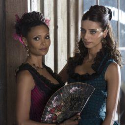 close up shot westworld characters maeve and clementine with a braided updo and half updo hairstyle, wearing costume dresses on set
