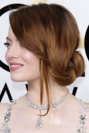 side view of emma stone with a side sweeping undone bun updo at golden globes