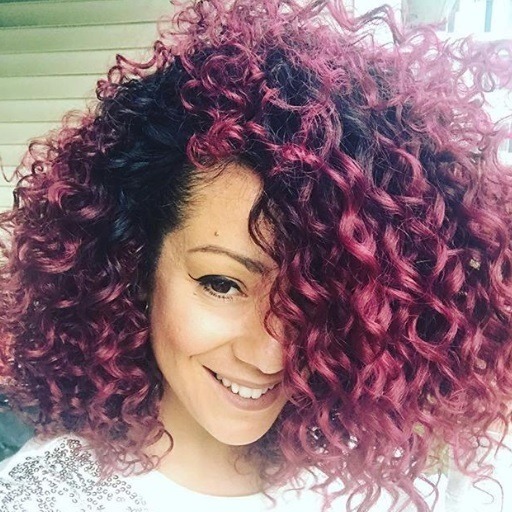 close up shot of woman with medium length red violet natural curls, wearing sparkly jumper
