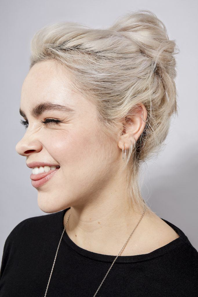 Woman with platinum blonde hair in a messy bun