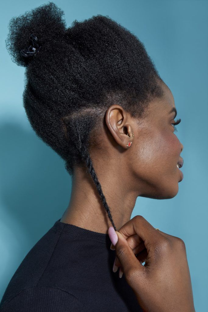 back view of a woman with natural black hair pulling down a twisted section