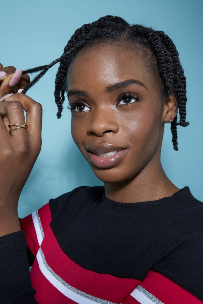woman with natural black hair styling her hair by twisting small sections