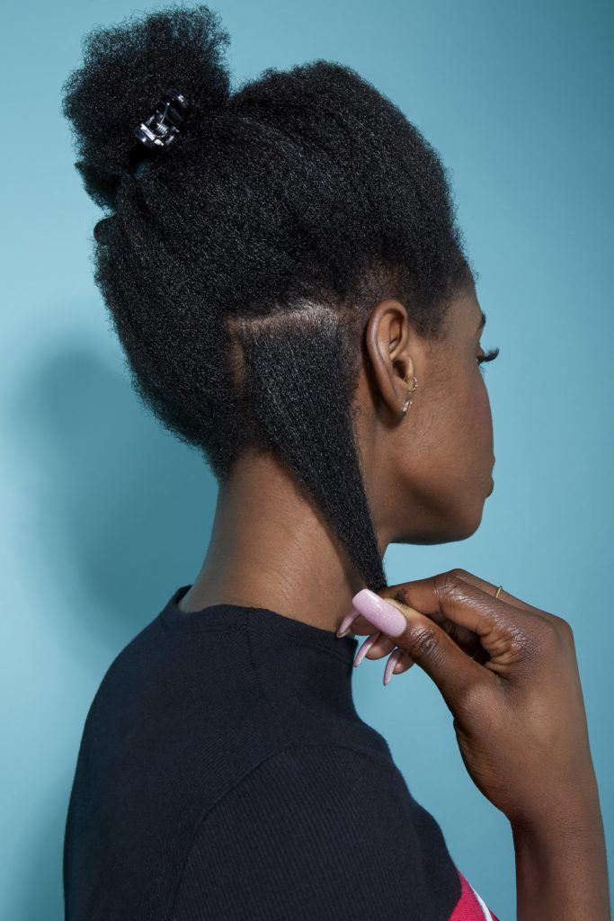back view of a woman with natural black hair pulling out a small section to style