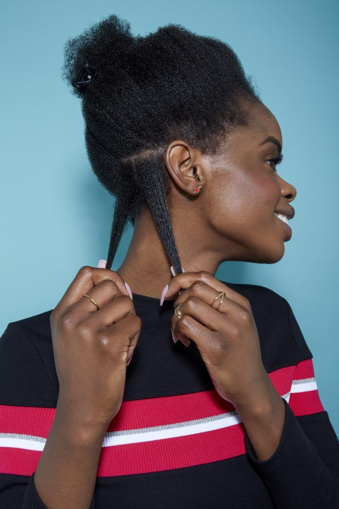 woman with natural black hair pulling down two sections of her hair to style