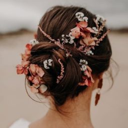Wedding updos: Back view of a brunette woman with her hair in a twisted updo with pink, peach and white flowers in