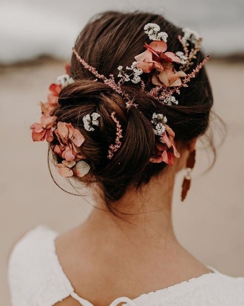 Wedding updos: Back view of a brunette woman with her hair in a twisted updo with pink, peach and white flowers in