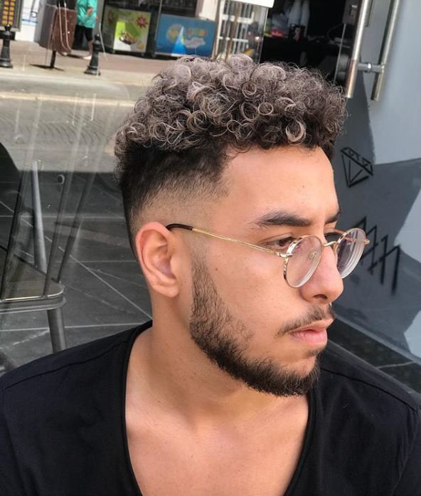 male in barber chair with natural afro curly hair undercut with grey tips