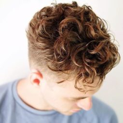 male with hair styled in large loose brown curly hair undercut