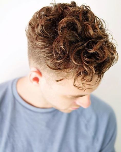 male with hair styled in large loose brown curly hair undercut
