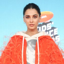Ones to watch: Naomi Scott with brown hair in updo wearing a bright orange fluffy coat and hoodie.