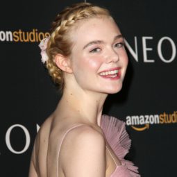 Elle Fanning with her golden blonde hair styled into a braided crown updo with floral clips in it
