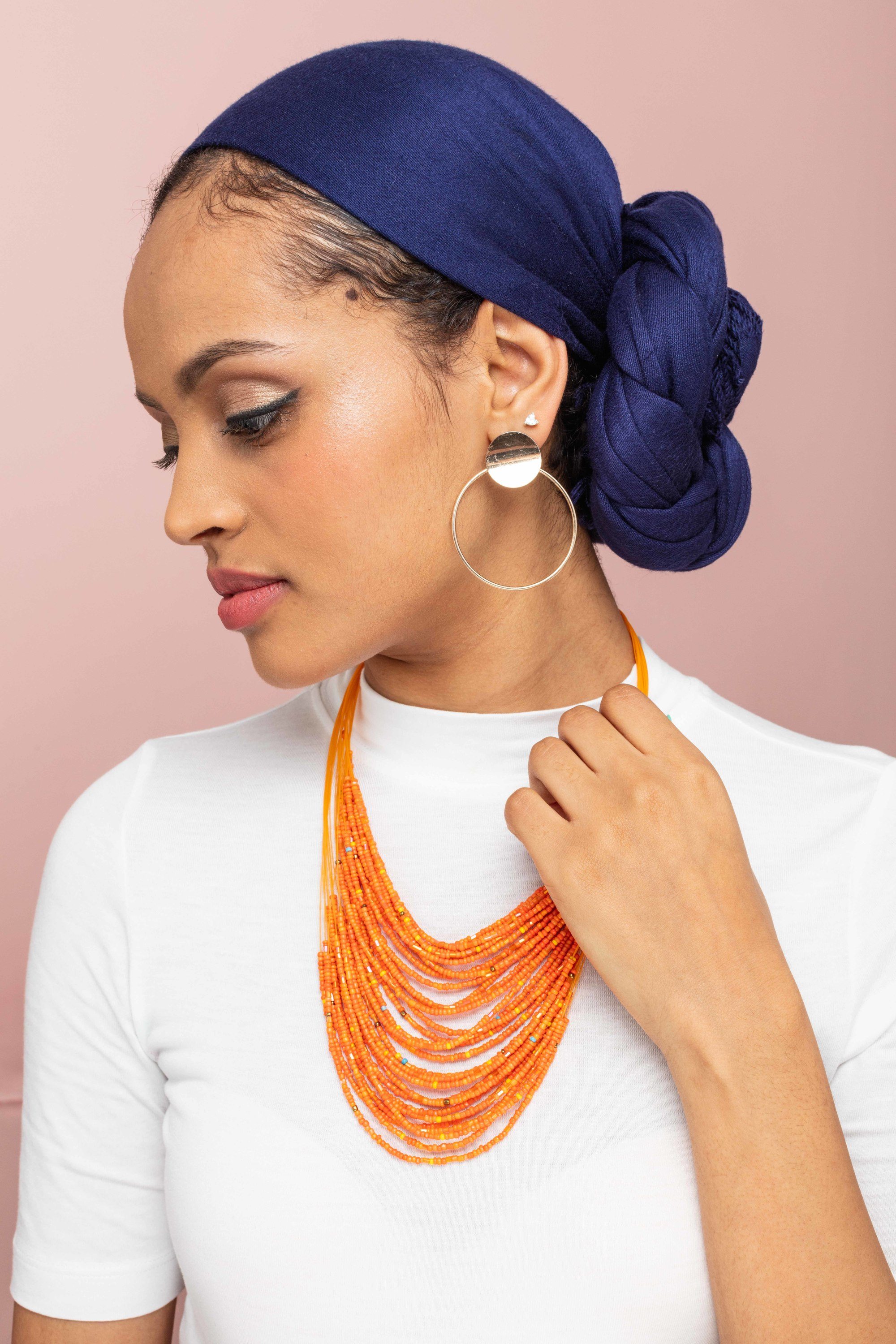 How to wear a headscarf: Woman with purple headscarf twisted into a low side bun.