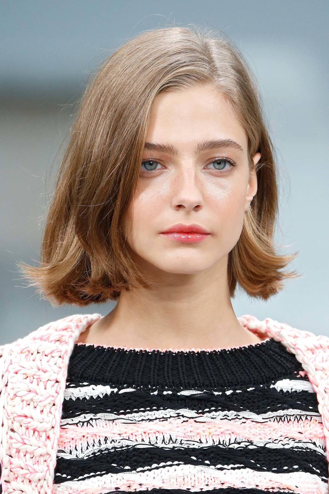Woman with thick brunette hair in a side parted bob with flicked out ends