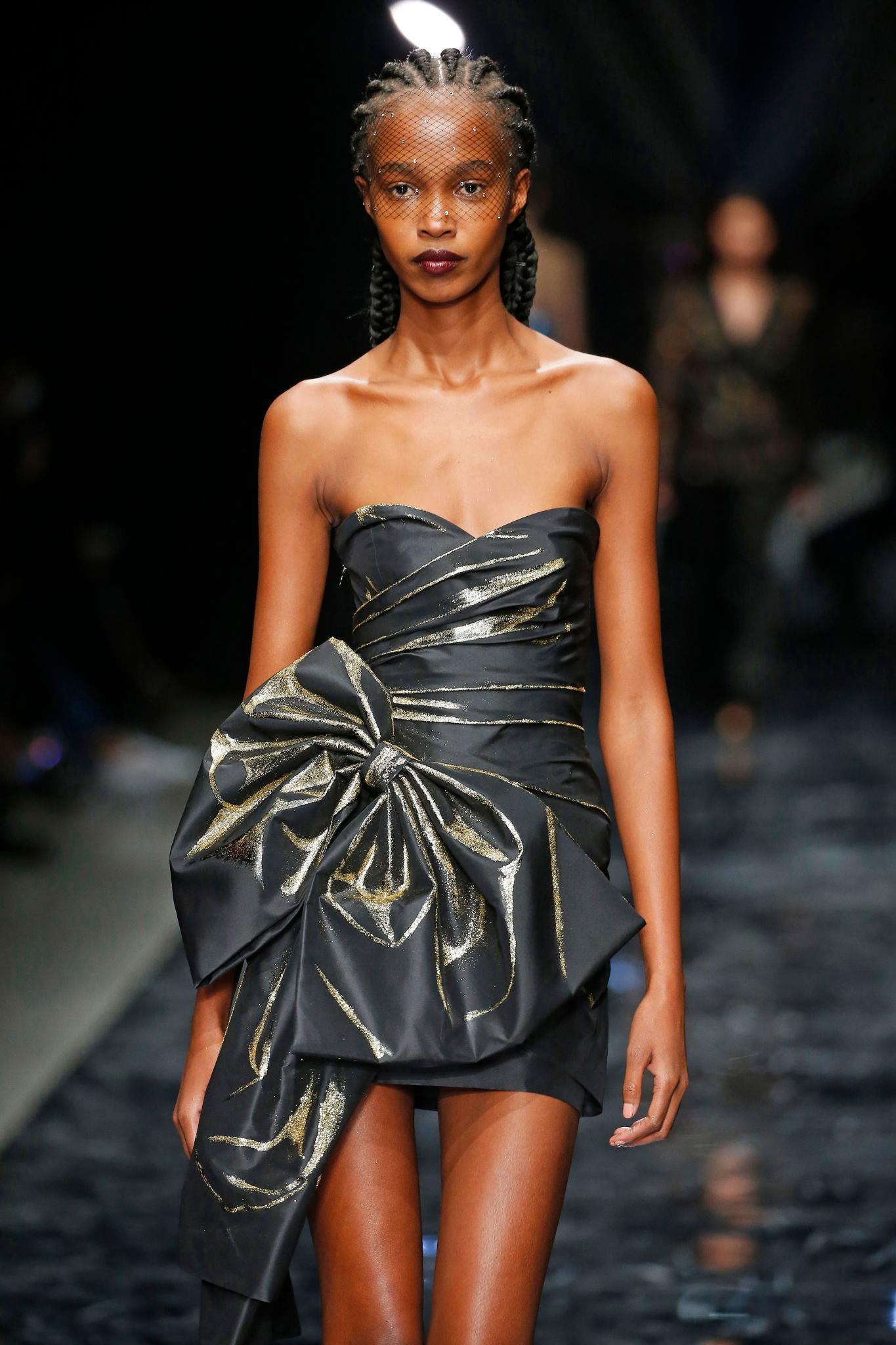 Haute Couture: Model with cornrow braids with net veil wearing a black strapless dress.