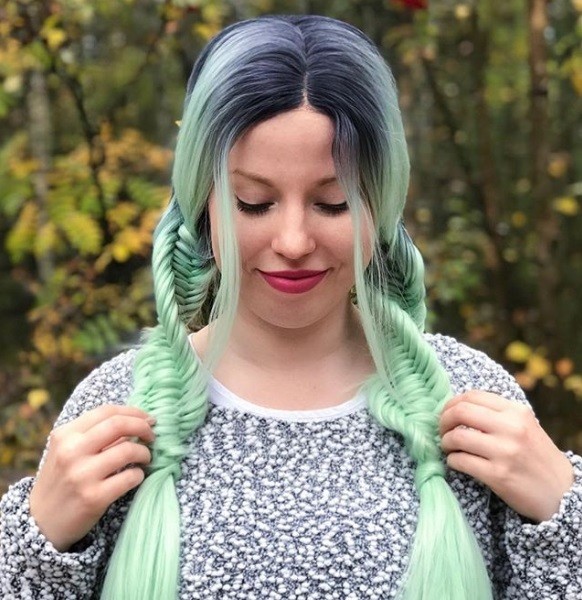 Woman with pastel mint green hair styled in two pigtail DNA braids.