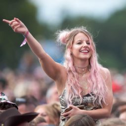 Woman in the crowd at a festival with long wavy pink hair in half up space buns with hidden braids and hair rings