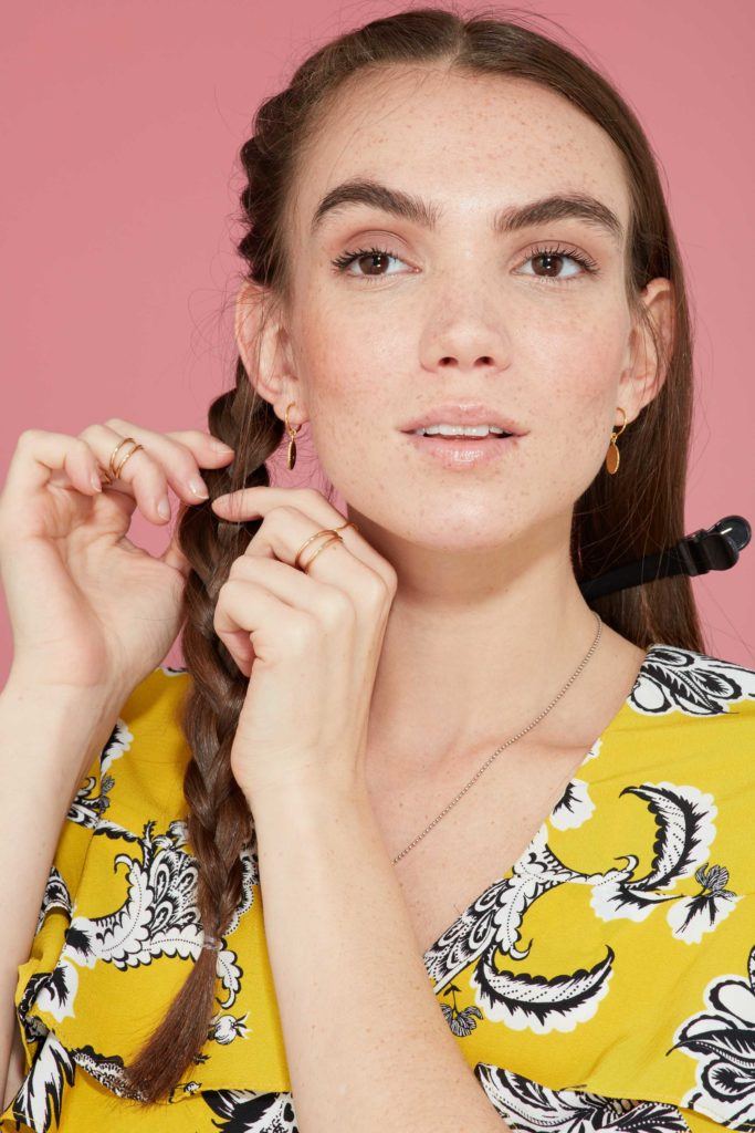 close up of a brunette model pancaking (pulling apart) her braid to make it fuller