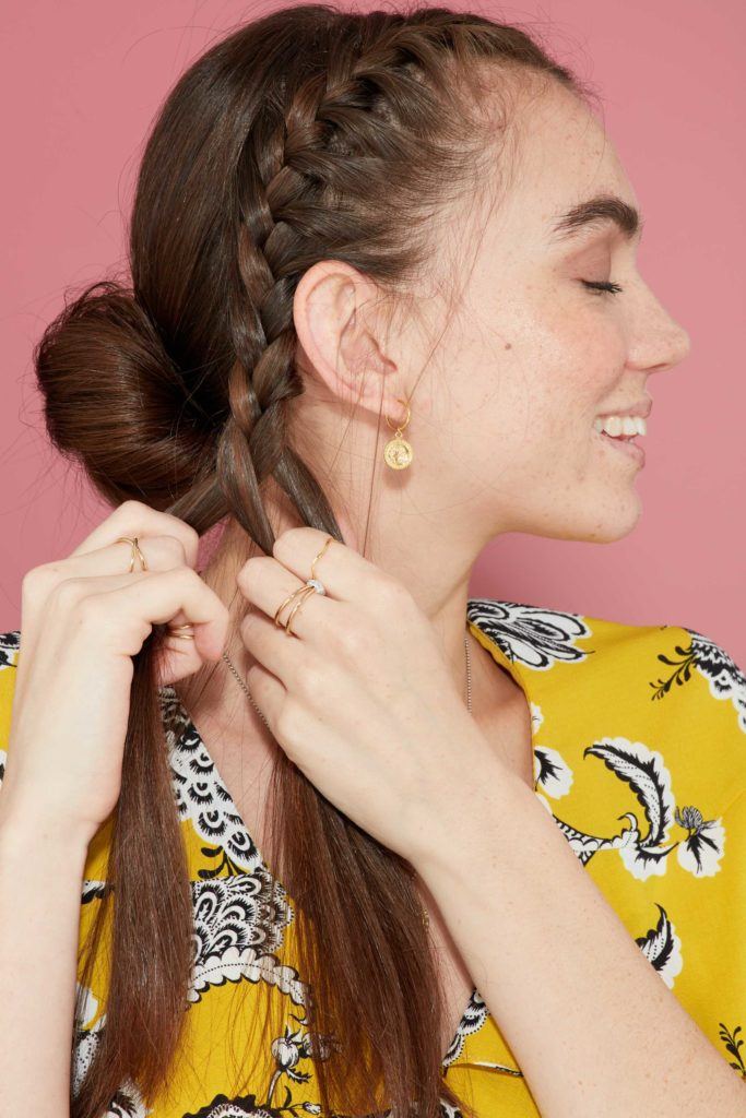 close up profile view of brunette model french braiding the front section of her hair