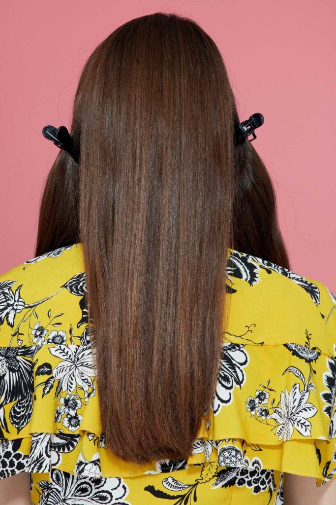 back view of a brunette model with long straight hair clipped into sections