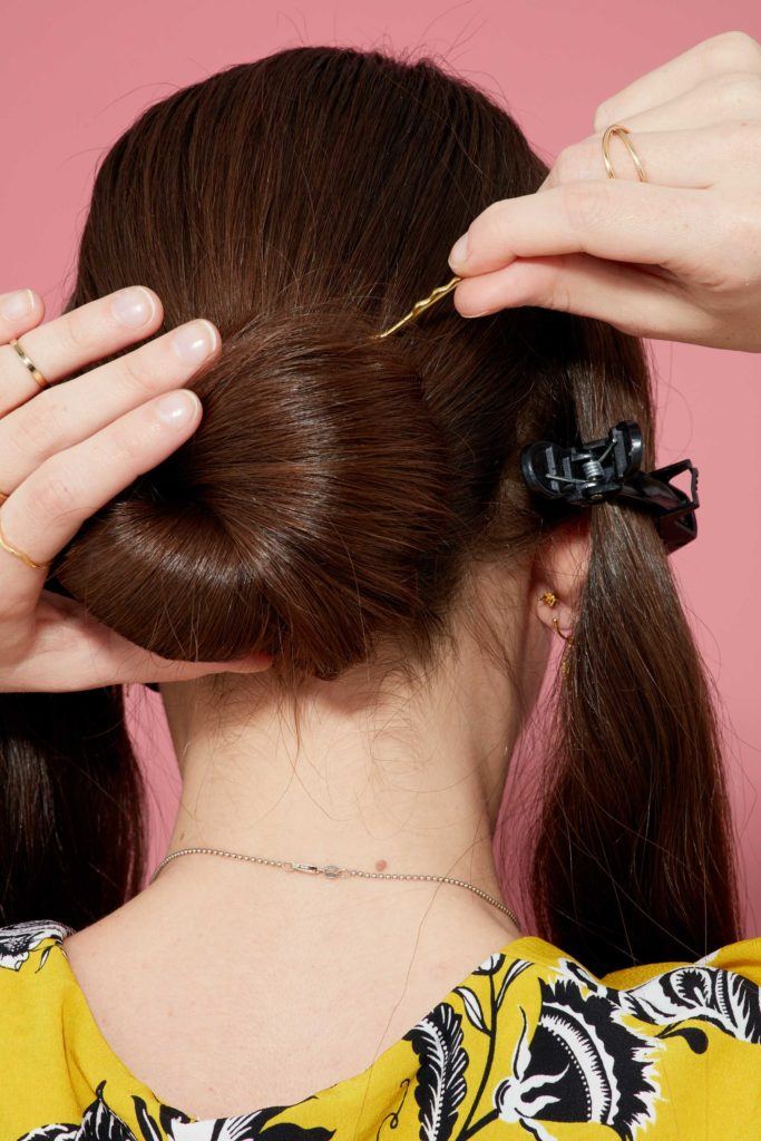 close up view from behind of a brunette model wrapping her hair into a bun