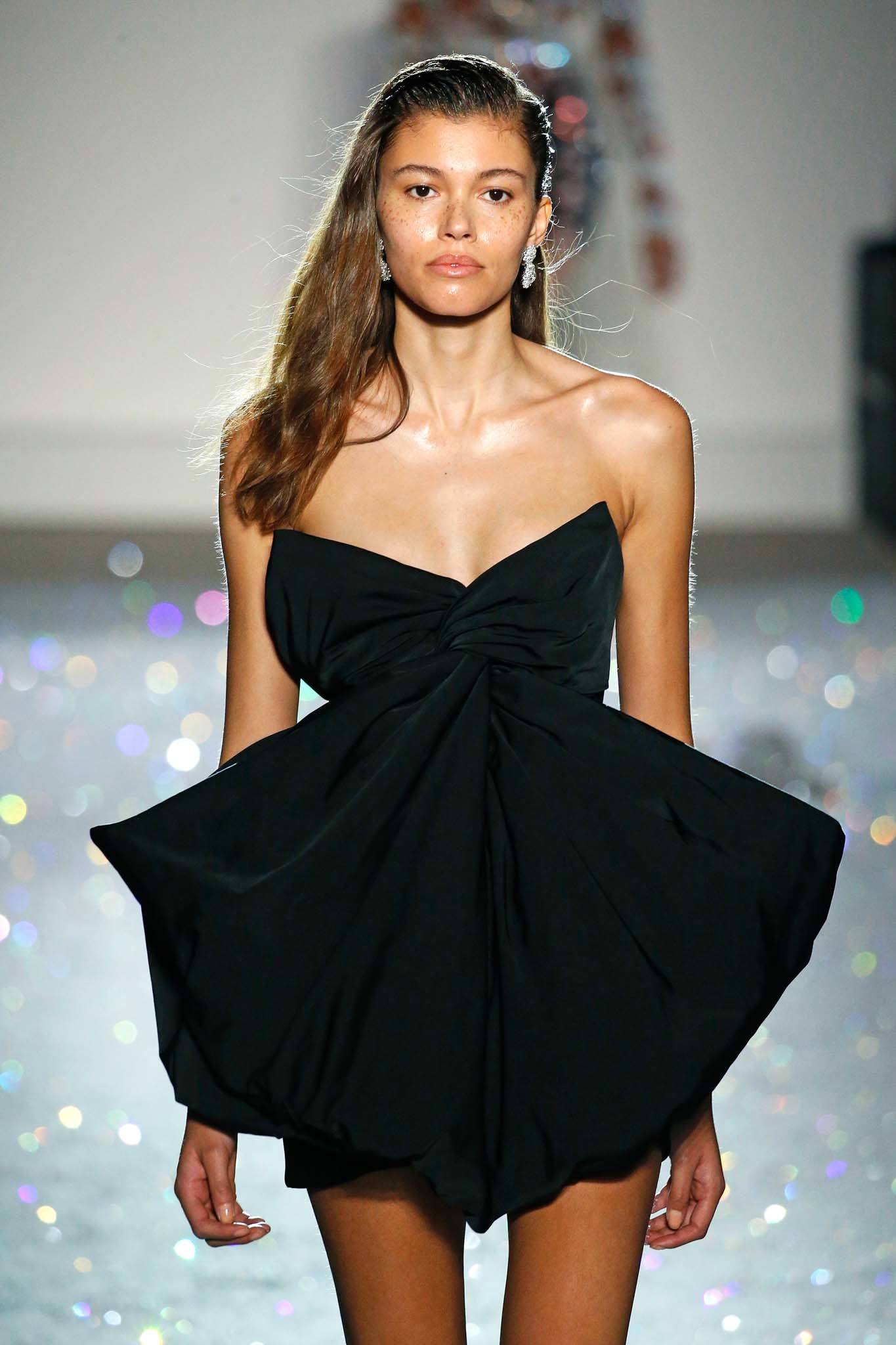 Haute Couture: Model on Giambattista Valli SS19 runway with wavy brown hair with wet look finish wearing a strapless black dress.