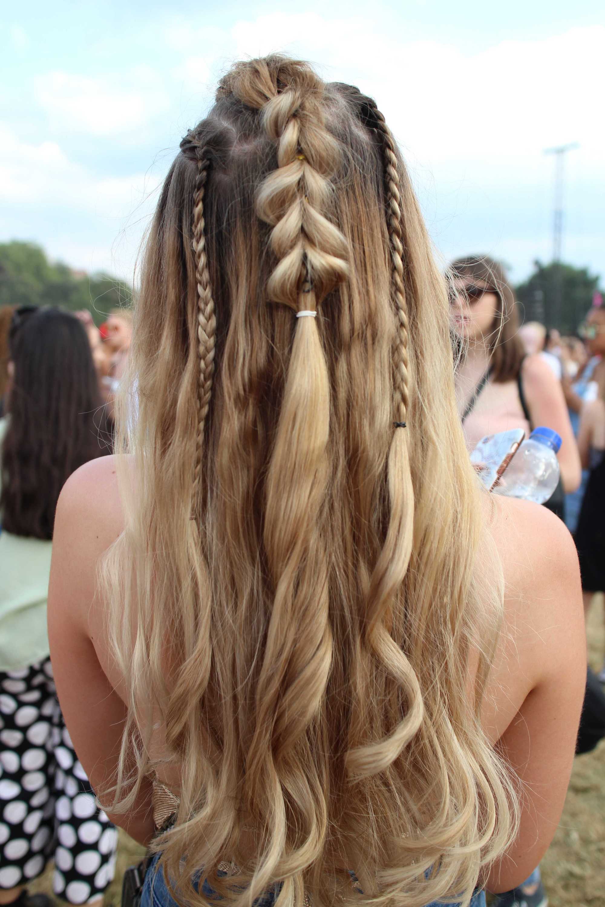 Back view of a woman at Lovebox festival with curled long blonde hair in a half-up pull through braid style with hidden braids.