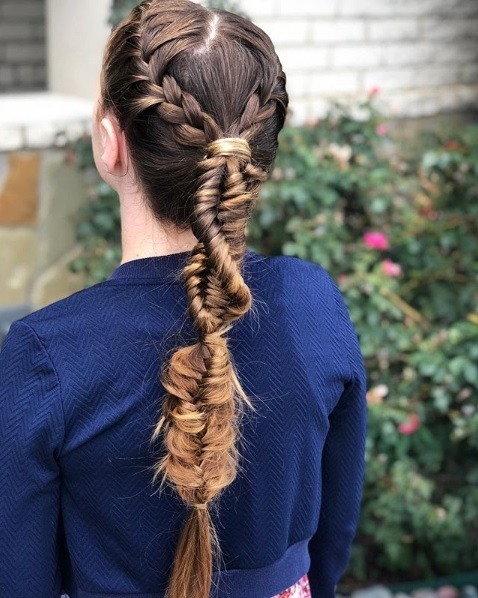 Back view of a woman with very long brunette hair in a braided ponytail made up of DNA braids and other mix and match braiding styles.