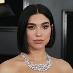 Red carpet hairstyles: Dua Lipa with dark brown straight blunt bob on red carpet wearing a strapless pale blue dress and diamond necklace.