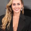 Red carpet hairstyles: Miley Cyrus with softly swept waves on her blonde hair with a black blazer jacket.