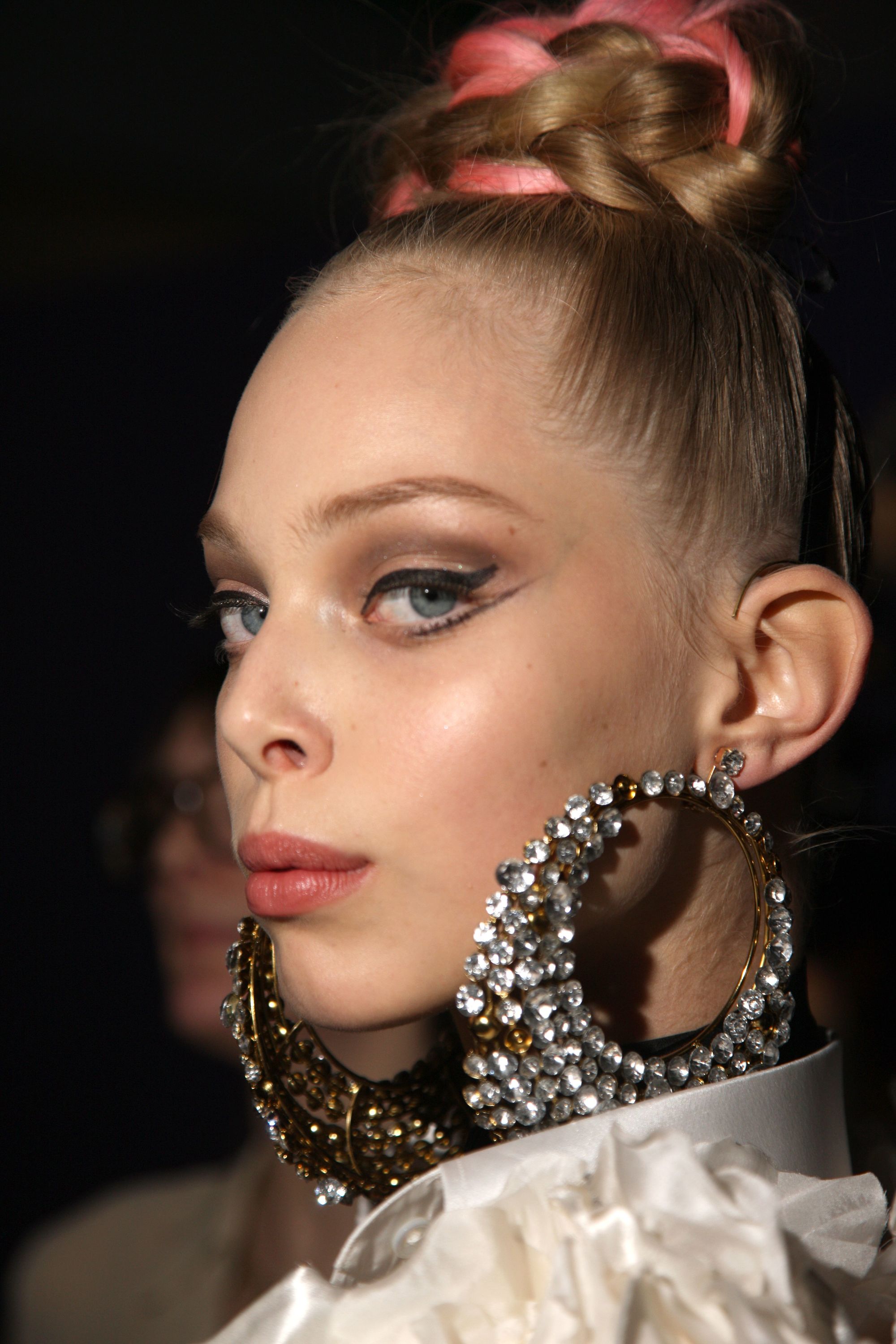 Knot bun hairstyle: Close-up shot of a blonde model with a braided high bun hairstyle with coloured streaks