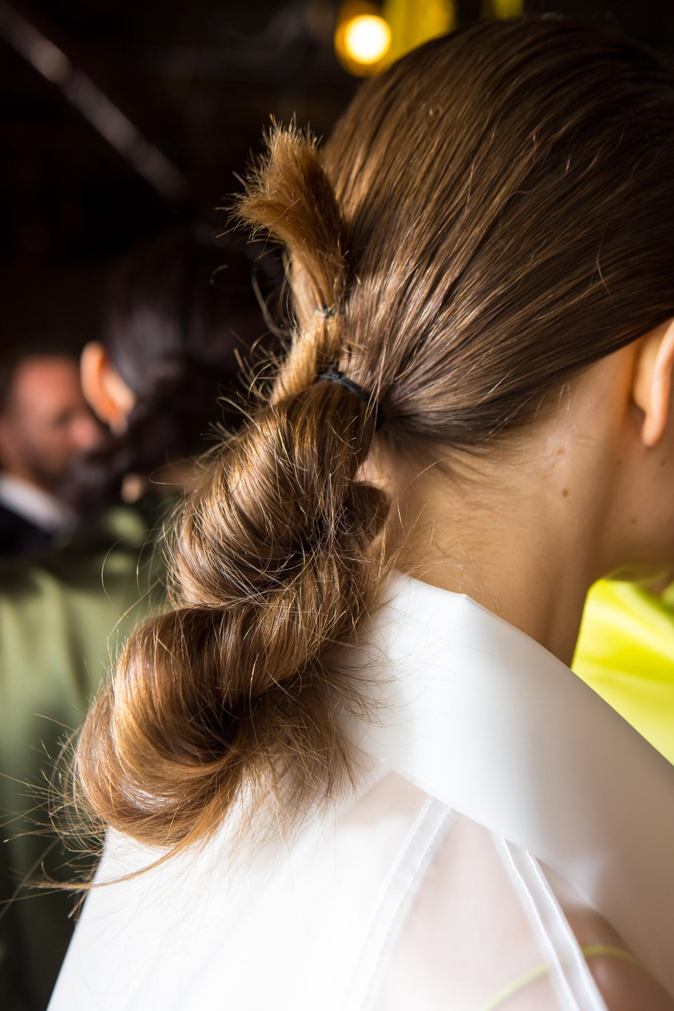 NYFW Catwalk Trends: Model with light brown straight hair in a looped twisted bun updo wearing a white shirt at Dion Lee FW19 show.