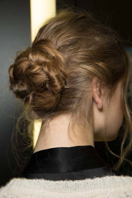 Knot bun hairstyle: Close-up shot from behind of a brunette model with a messy braided bun with wispy strands