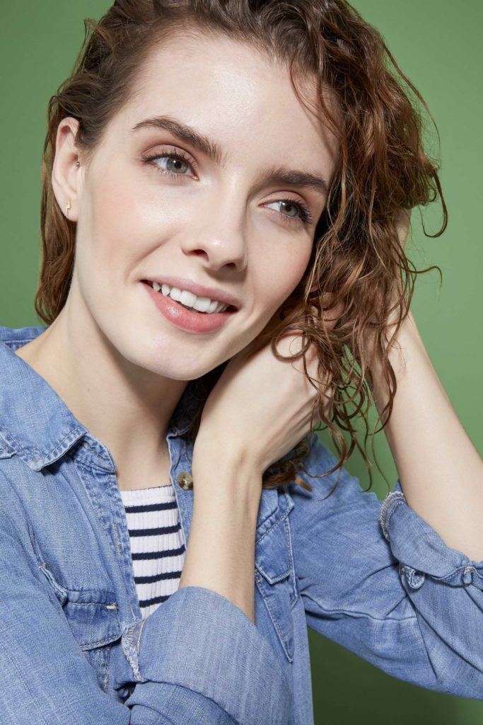 How to scrunch hair tutorial: Close up of a woman with brunette curly hair scrunching her curls with her hands