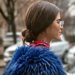 NYFW AW19 Street Style: Shot of a woman with chestnut brown hair styled into low bun, wearing sunglasses with plaid top and blue furry jacket
