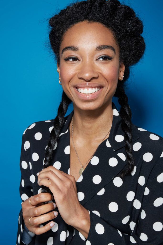 Blow out natural hair: Smiling natural haired woman with half of her hair up and the bottom layers twisted into two rope braids.