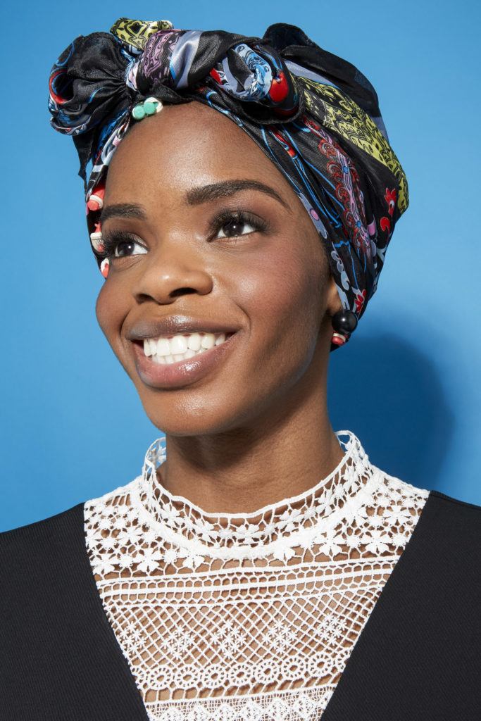 Perm rods on natural hair video step 4: Close up shot a model with natural hair wrapped up in a silk scarf posing in a studio setting