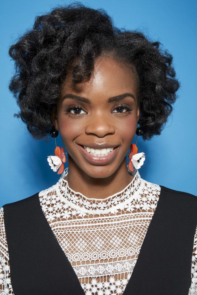 Perm rods on natural hair video step 8: Close up shot of woman with medium dark brown curls smiling in a studio setting