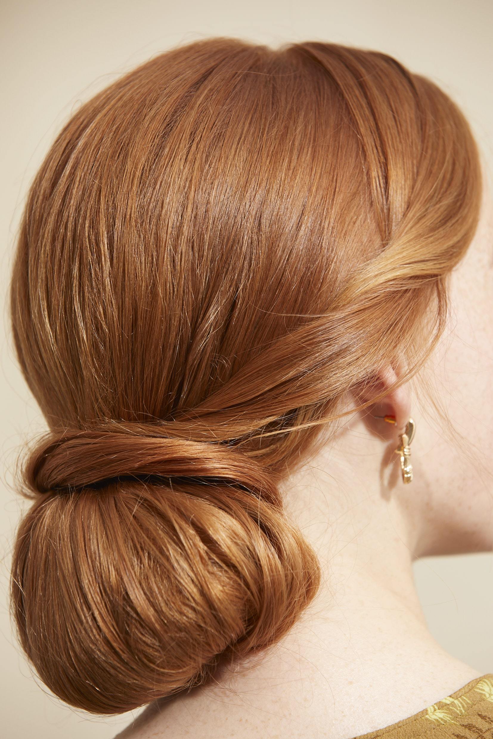 Woman with red hair styled into a retro twisted low bun