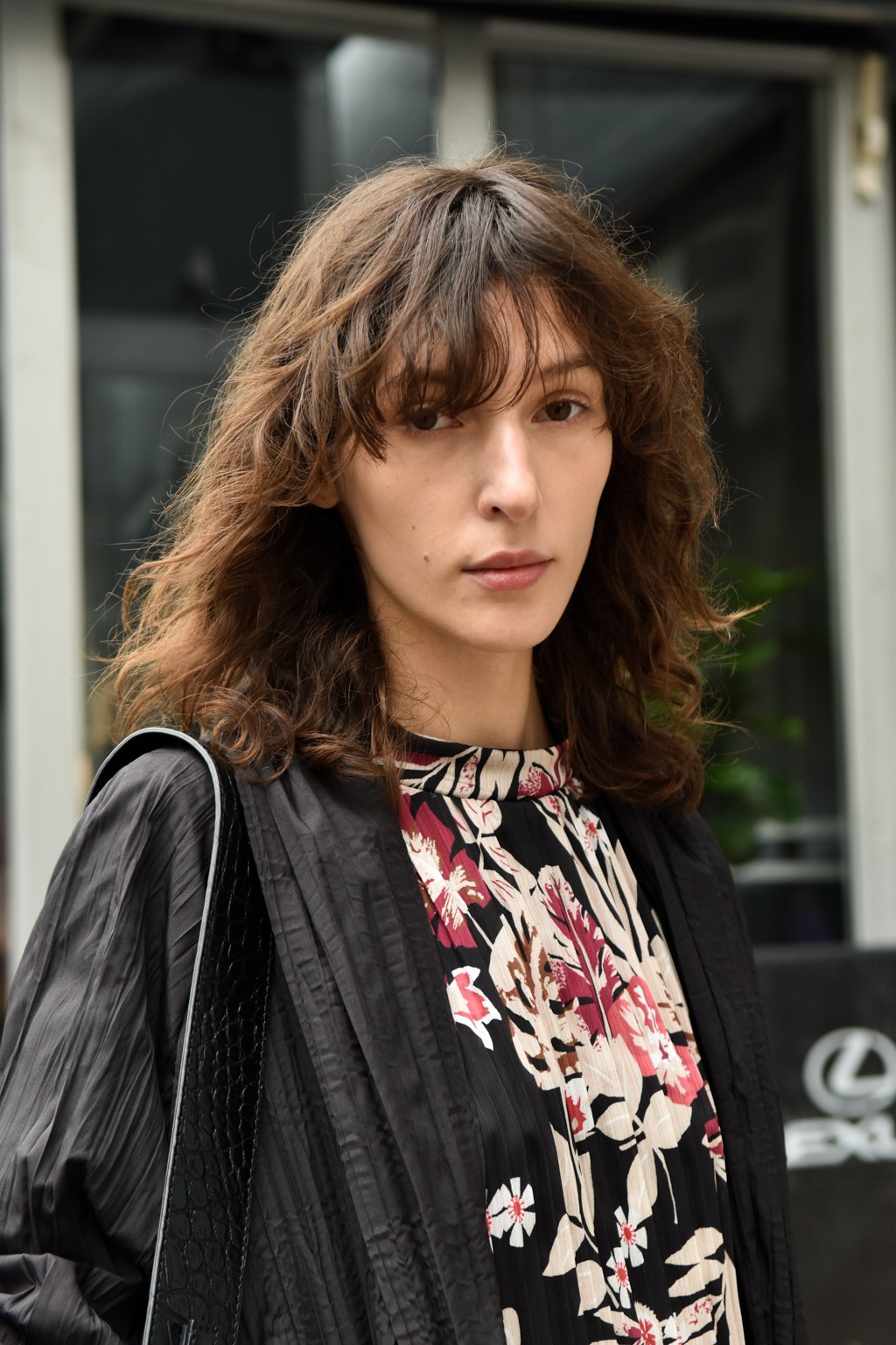 Hair treatment guide: Woman with medium brown shaggy hair with fringe, wearing leather jacket and floral top