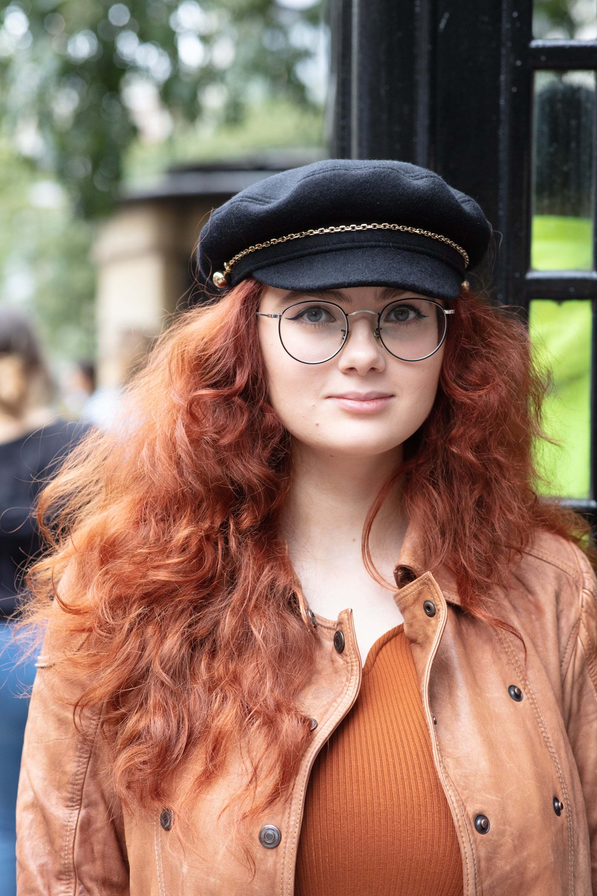 Hair treatment guide: Woman with long curly copper hair, wearing beige jacket with a baker boy hat
