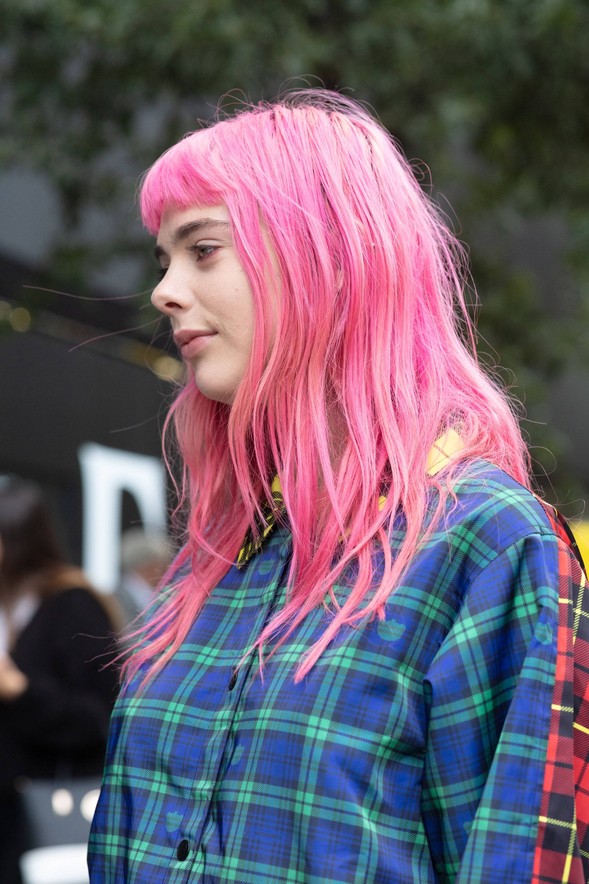 Hair treatment guide: Woman with medium neon pink hair with a micro fringe, wearing checked shirt